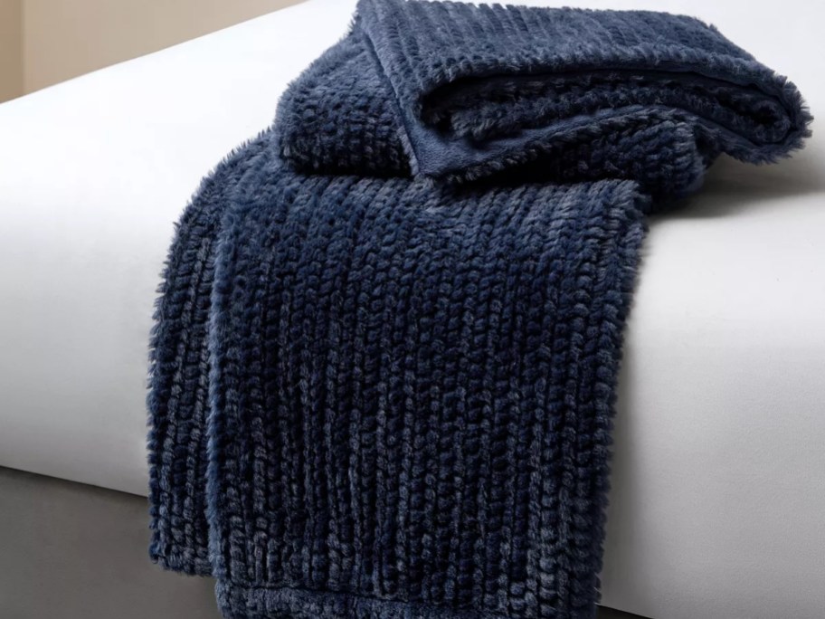 navy faux fur knit look blanket folded on the end of a bed