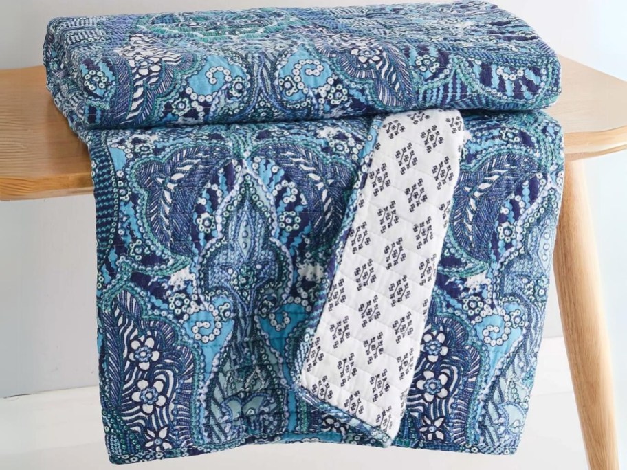 blue medallion reversible quilted throw on a bench