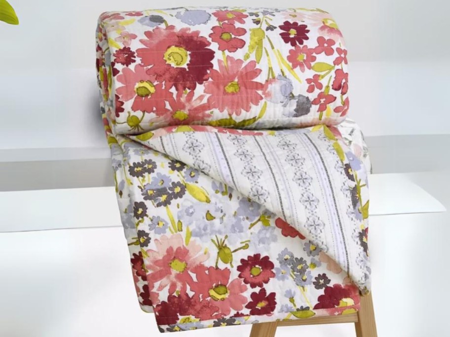 multi color floral quilted throw folded on a bench