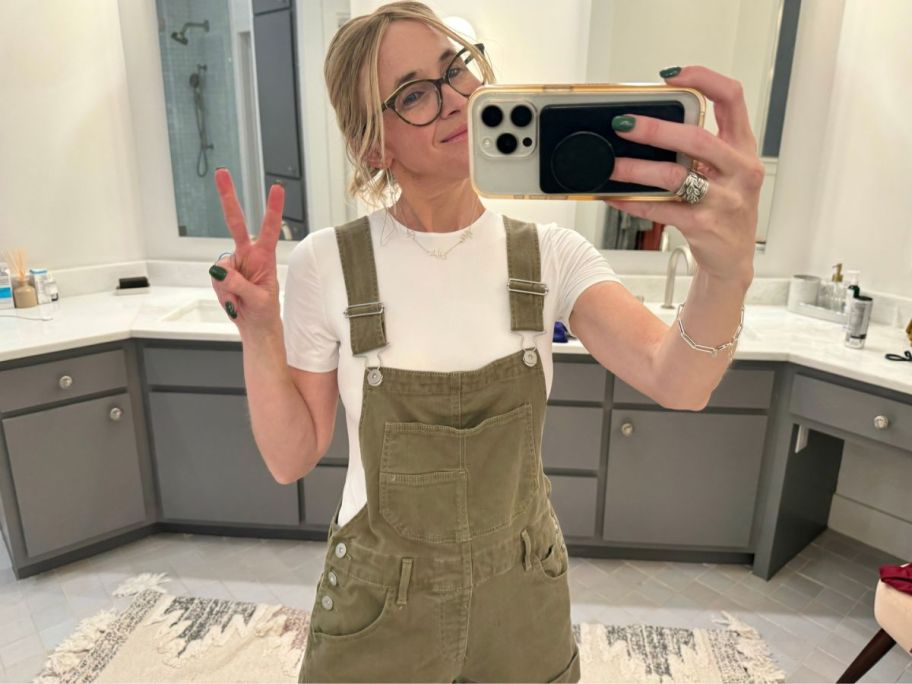 Woman taking a picture of herself in the mirror wearing a Mangopop bodysuit with overalls