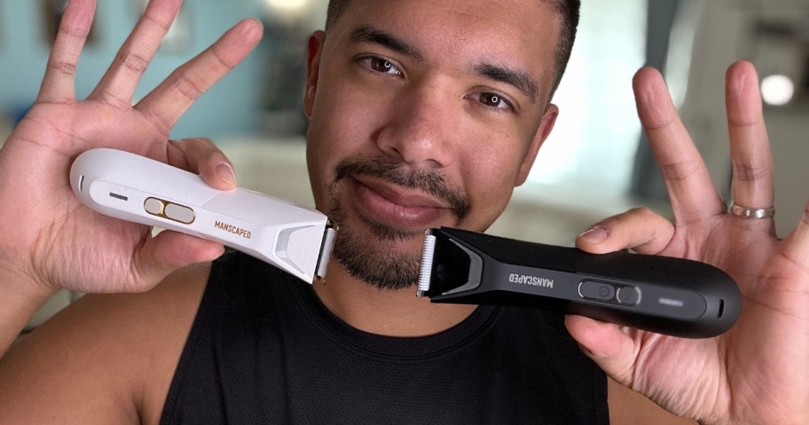 Shane (man) holding white and black Manscaped trimmers in each hand and smiling at the camera