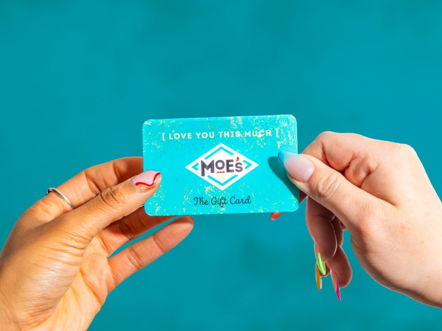 two hands holding a Moe's gift card