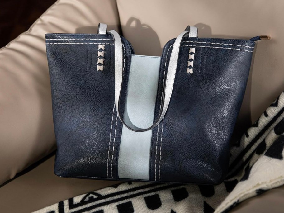 blue and gray leather tote sitting on leather couch