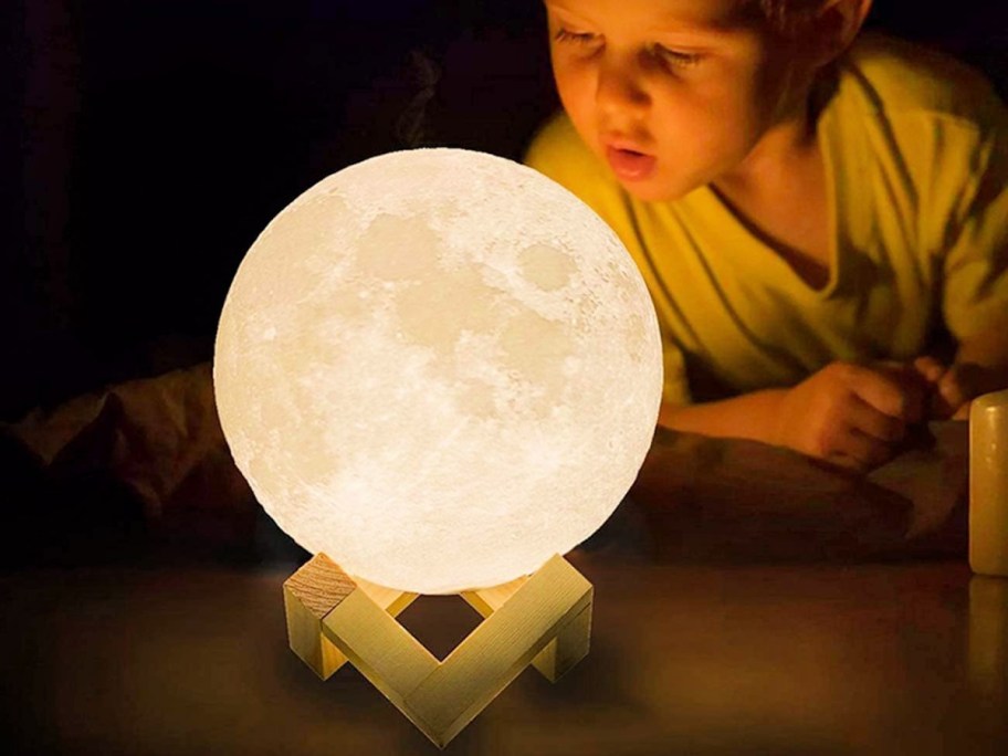 little boy looking at a moon lamp