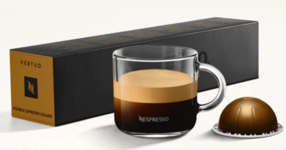 cup of coffee next to a box of Nespresso pods and single pod