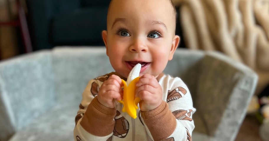 baby holding banana teether