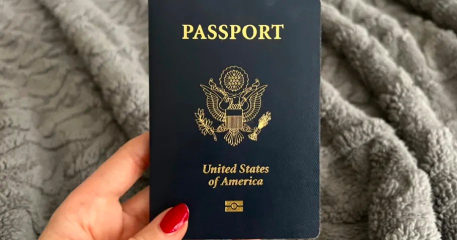 hand holding passport over gray blanket