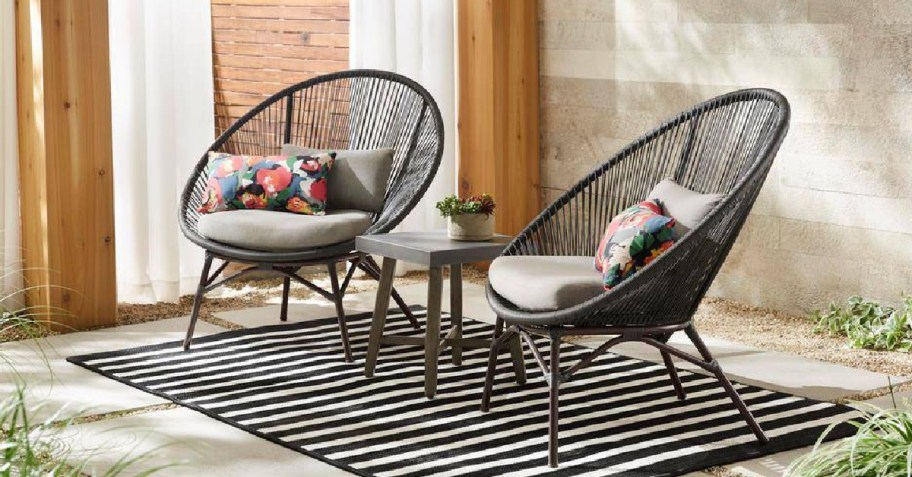patio chairs outdoors on a rug with a center table and cushions
