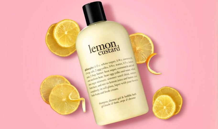 a bottle of philosophy 3 in 1 lemon custard shower gel on a pink background with lemon slices