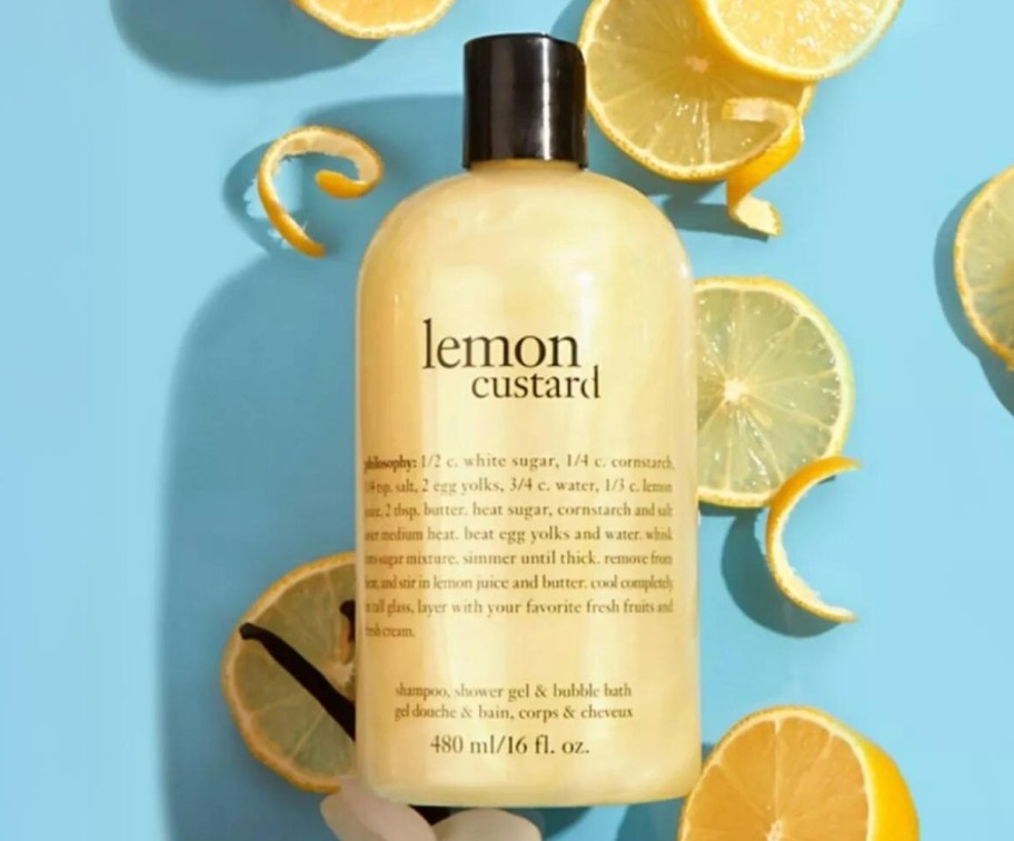 a bottle of philosophy 3 in 1 lemon custard shower gel on a blue background with lemon slices