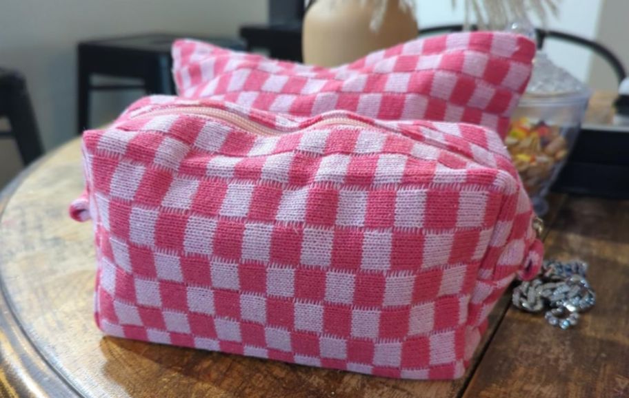 a set of 2 pink checkered knitted make up bags on a wooden table