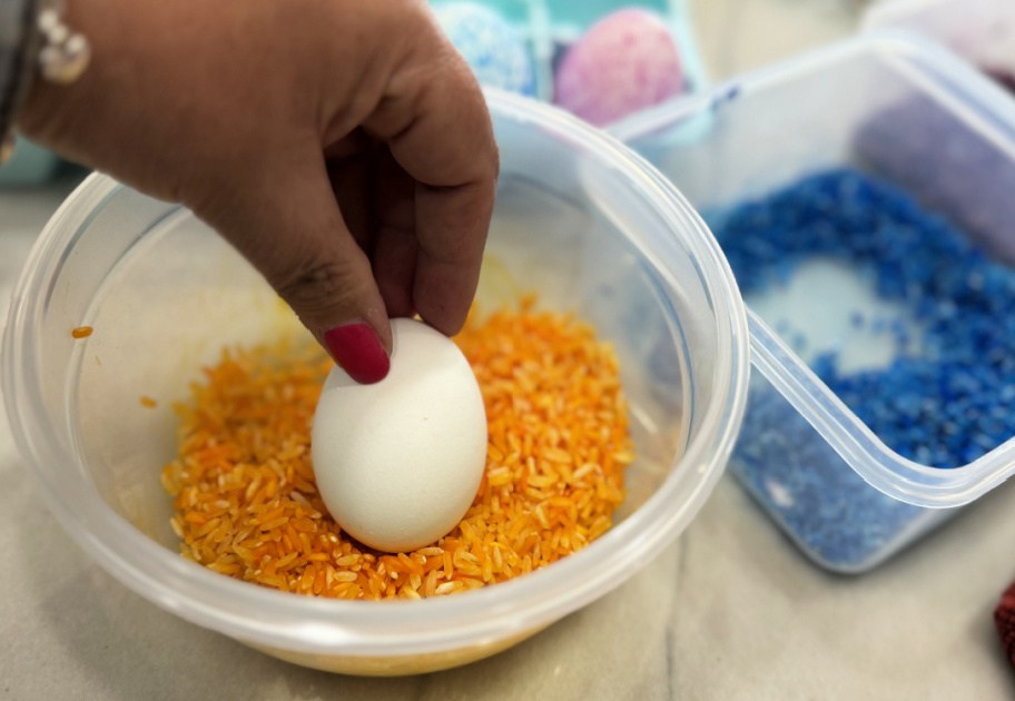 placing a hard-boiled egg into a container with dyed rice