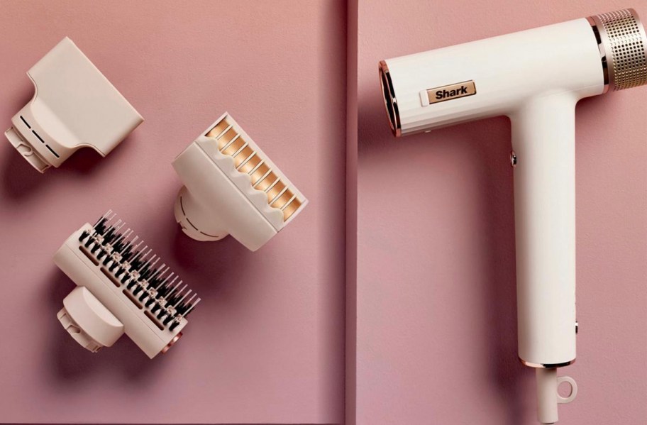white shark hair dryer with attachments laying on pink table