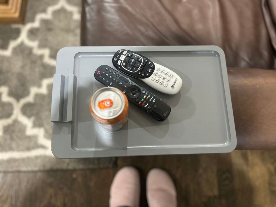 grey sofa arm tray on a brown sofa with remotes and a canned drink