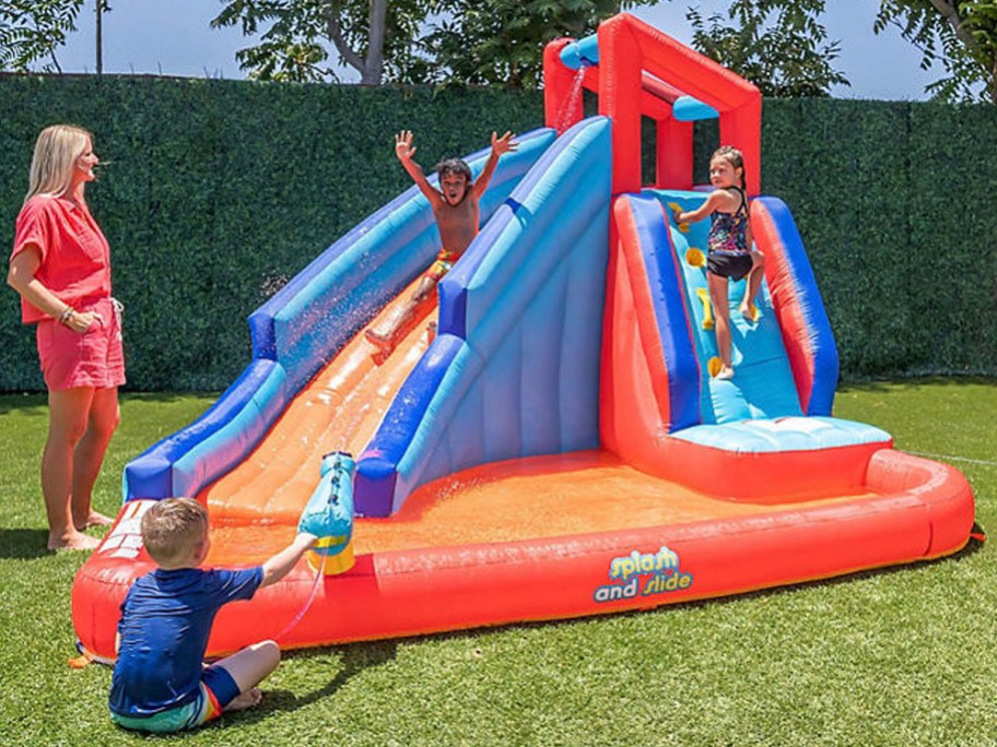 orange and blue inflatable water slide with kids playing on it