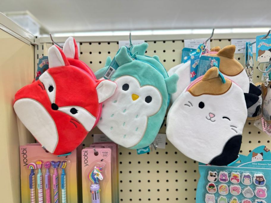 3 different Squishmallow shaped character zipper bags hanging on shelf 