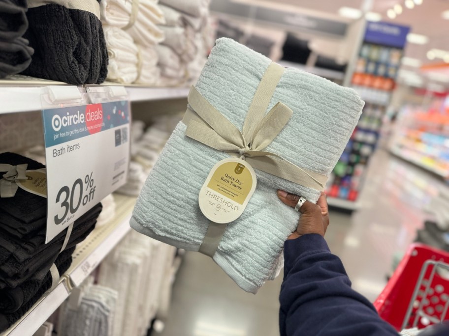 hand holding up a 2-pack of bath towels in a light blue color