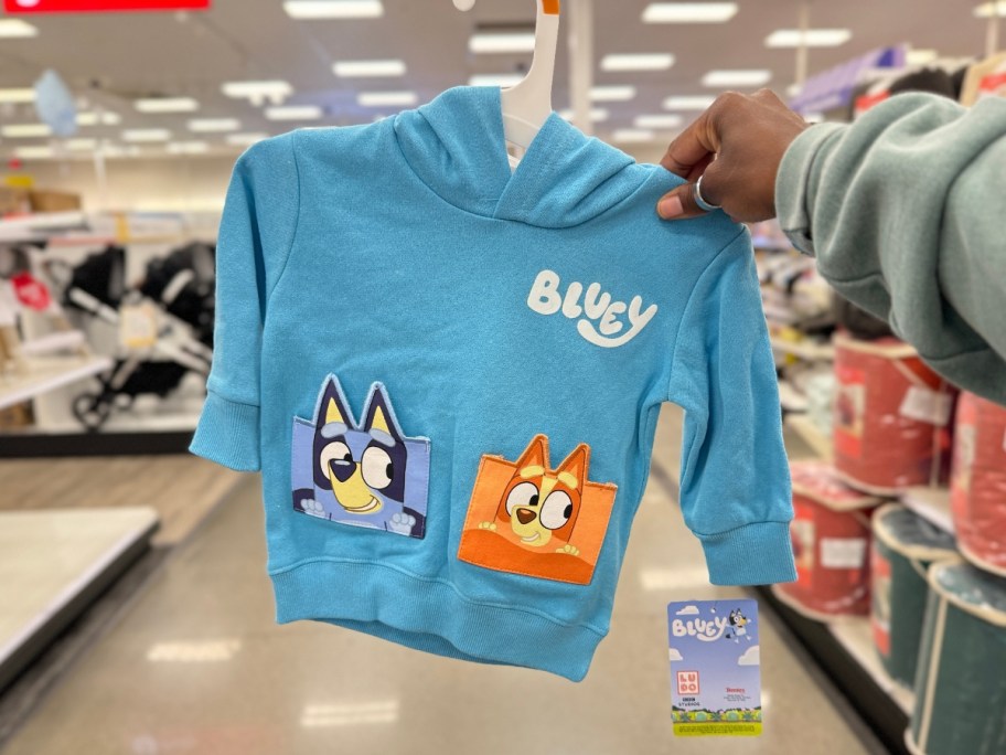 hand holding a toddler's blue fleece hoodie with Bluey and Bingo on it