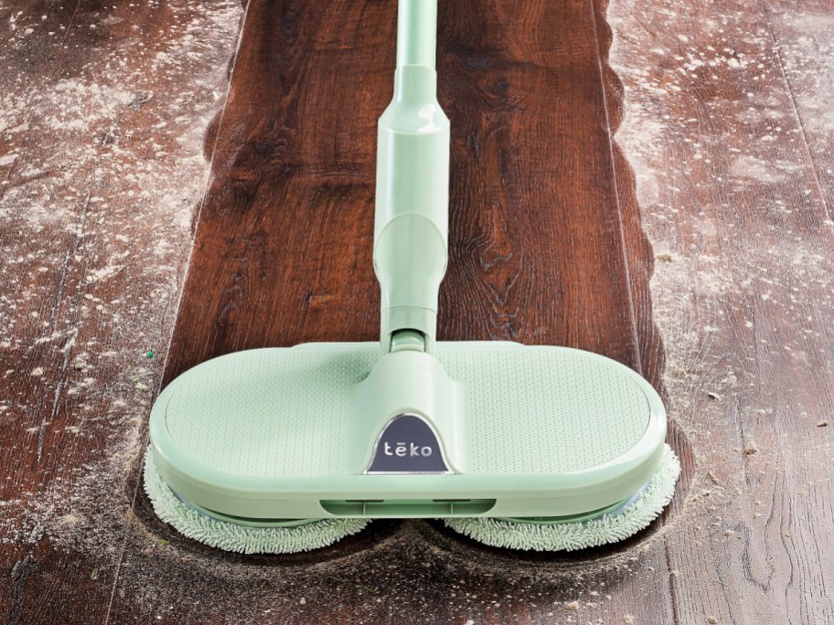 mint green Hover Scrubber Omni Cordless Dual-Head Mop cleaning a ptah on a wood floor