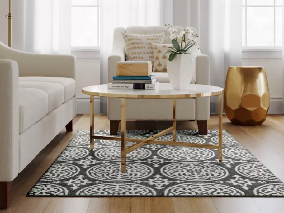 dark gray and white medallion rug with coffee table sitting on it next to white couches
