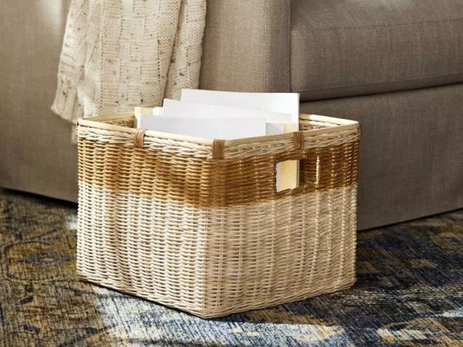 large square 2-tone rattan basket in the floor by a sofa