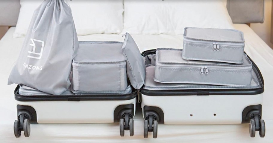 gray packing cubes inside white luggage laying on bed