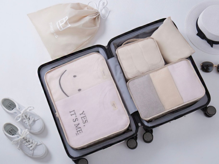 beige packing cubes inside luggage next to white shoes