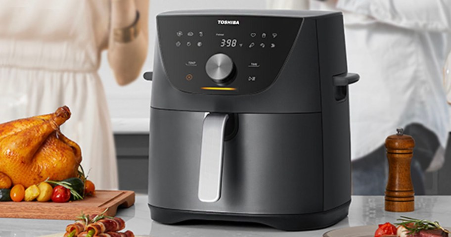black toshiba air fryer on counter next to plate with chicken 
