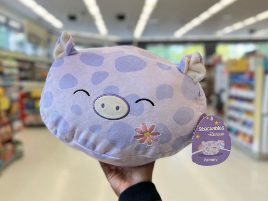 hand holding a purple spotted Squishmallows Pammy - Pig Plush Stackables