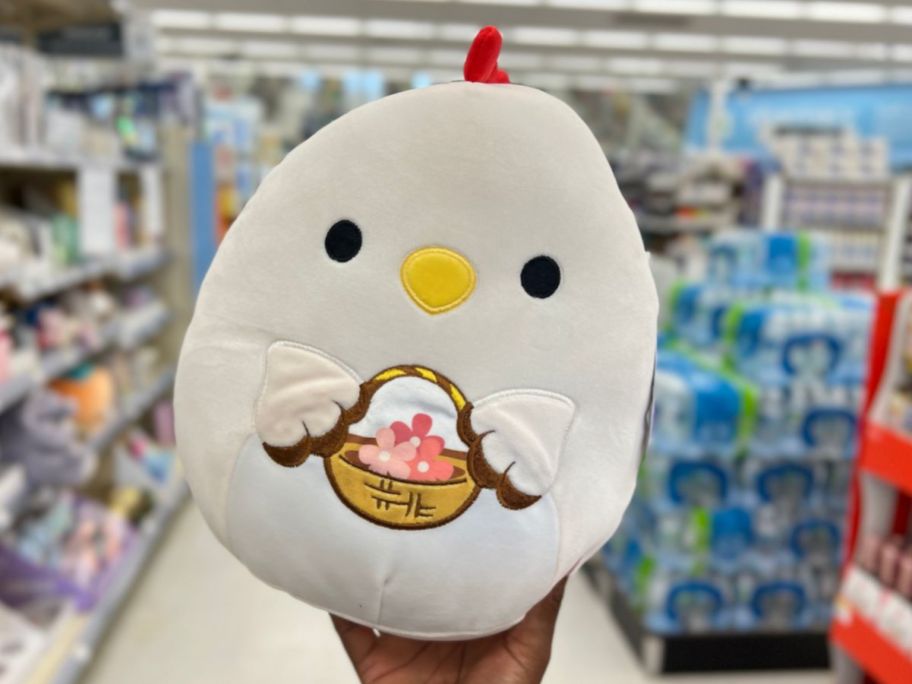hand holding a Squishmallows Todd the Rooster with an easter basket 