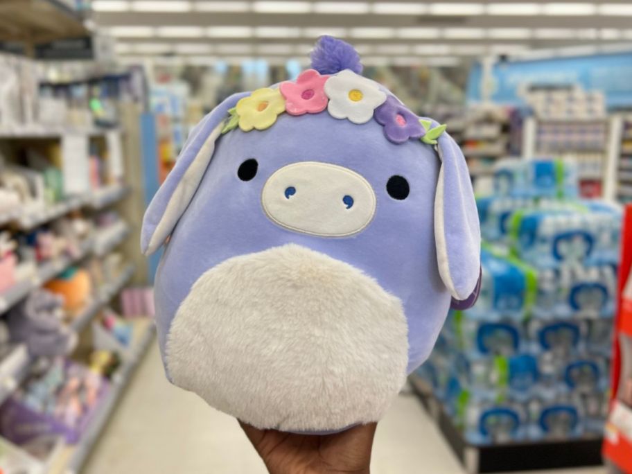 hand holding a purple and white Squishmallows Donkey With Floral Headband