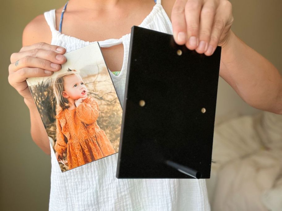 a womans hand displaying the back of an 8x10 Walgreens wood print with peg