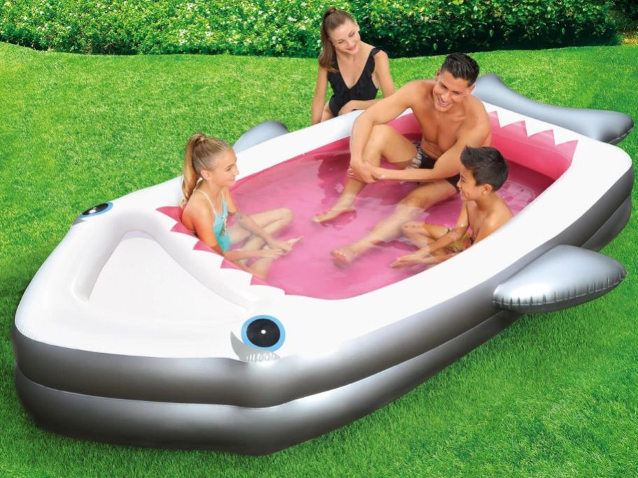 Two parents and two kids sitting in a shark shaped pool