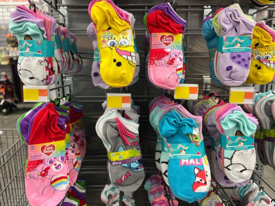 8 six packs of various walmart character sock on pegs displayed in a store