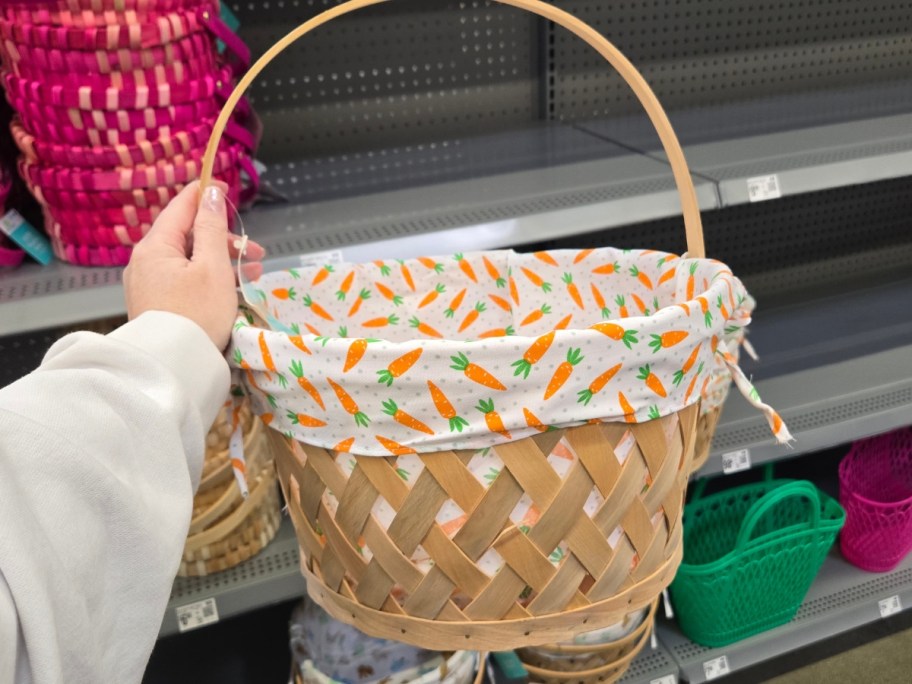 hand holding a woven Easter basket with a white fabric liner that has carrots on it