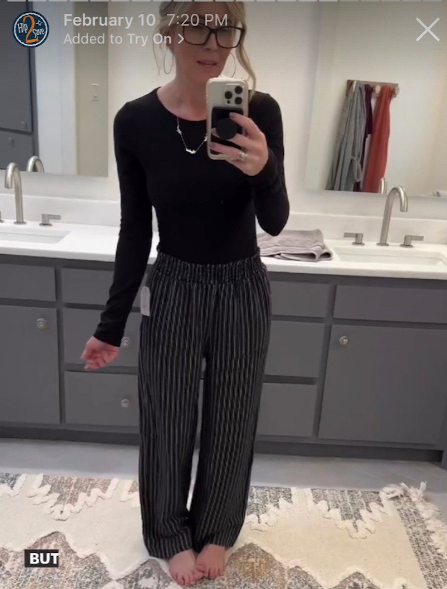 woman taking selfie wearing black shirt and pinstripe linen pants