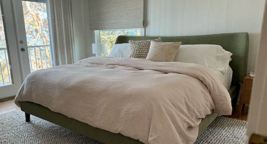 green upholstered bed with beige duvet and throw pillows