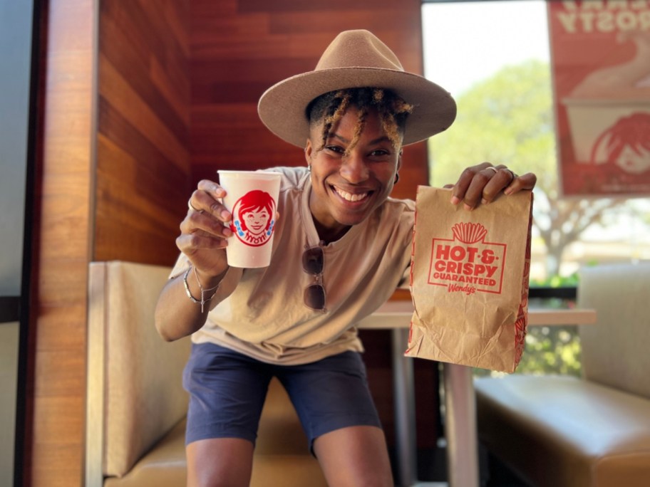 person wearing hat and holding Wendy's Frosty and paper bag