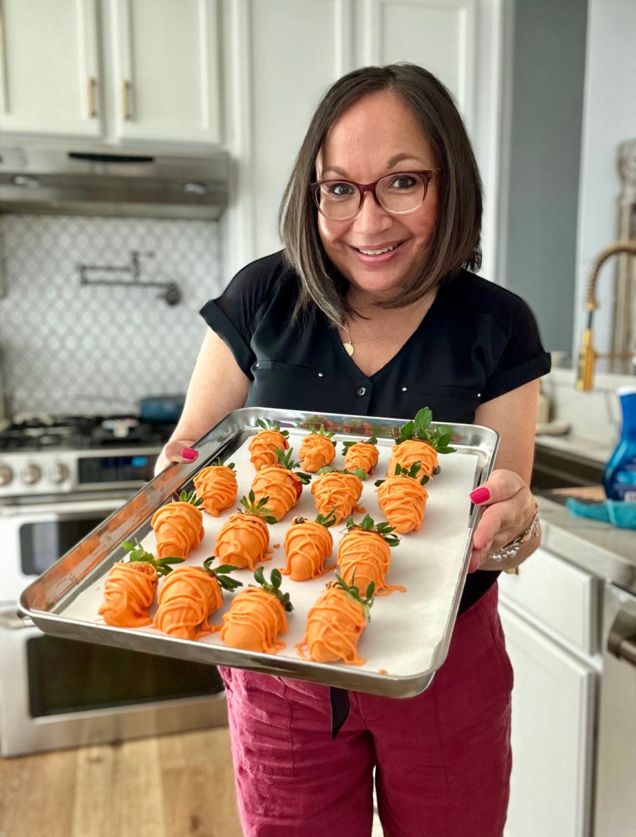 woman holding a tray of orange strawberry carrots