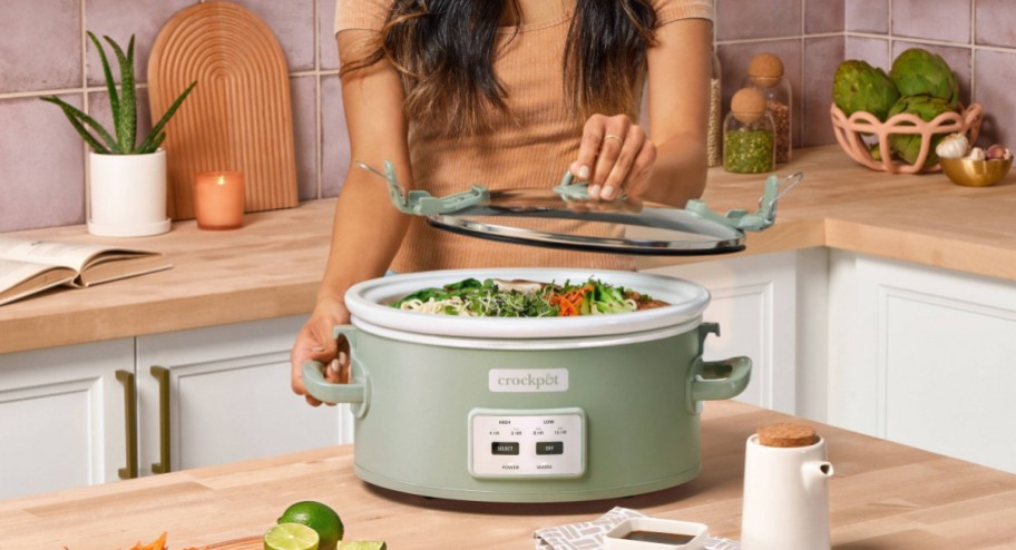 woman lifting crockpot lid with food in it