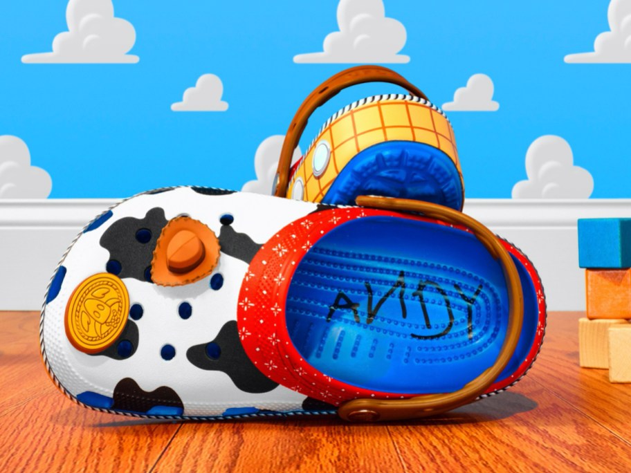 sheriff woody crocs sitting on floor with cloud wallpaper behind them