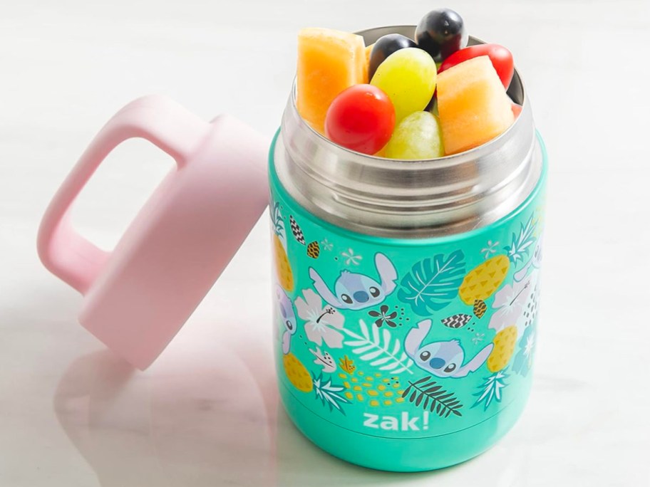 blue stitch food jar with fruit inside and pink lid leaning on it