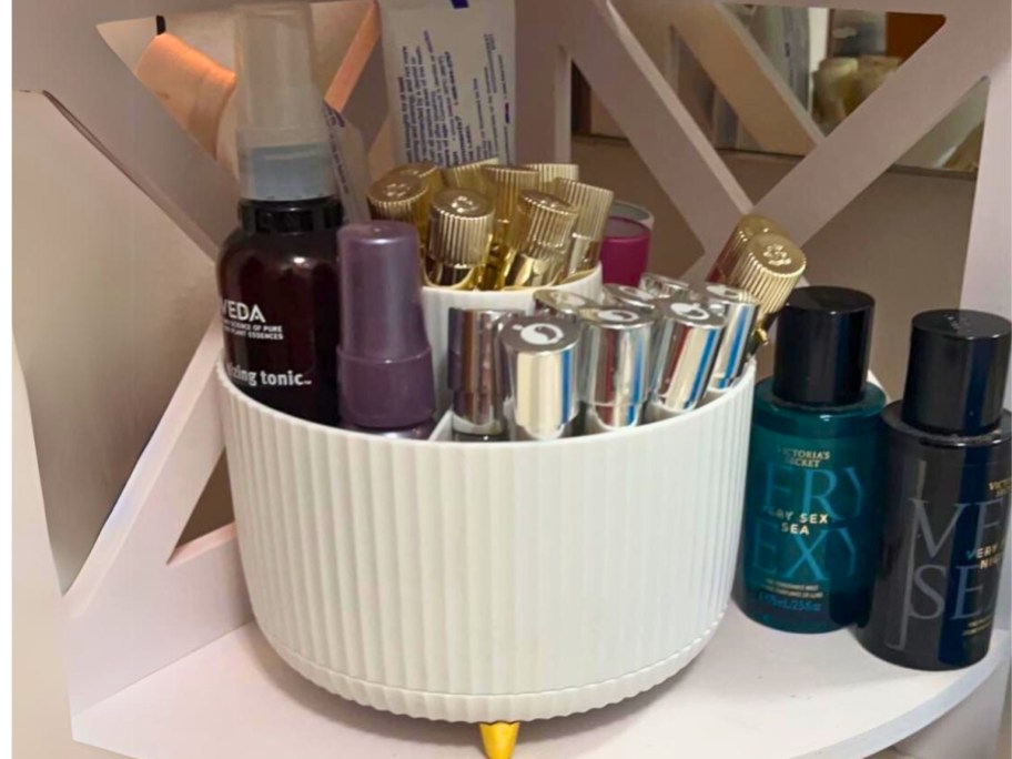white and gold Rotating Makeup Brush Organizer with makeup and hair products in it