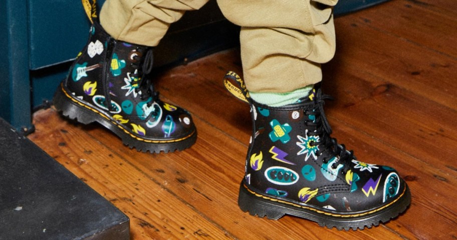 toddler wearing black, green, yellow, white sticker print Dr. Martens