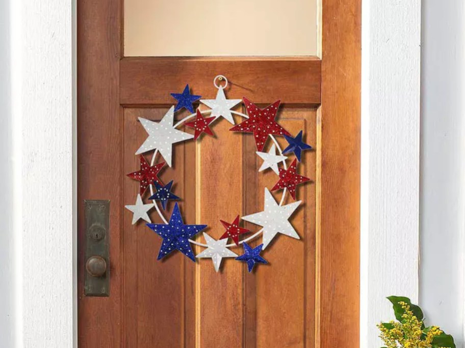 red, white, blue, patriotic metal star wreath on a wood door.