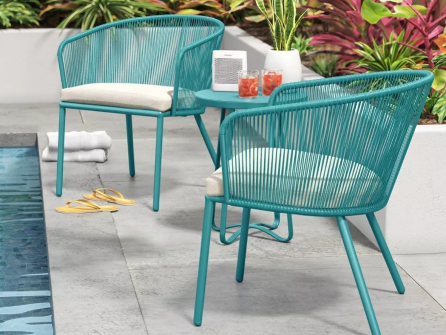 teal blue outdoor patio set with 2 chairs and side table by a swimming pool