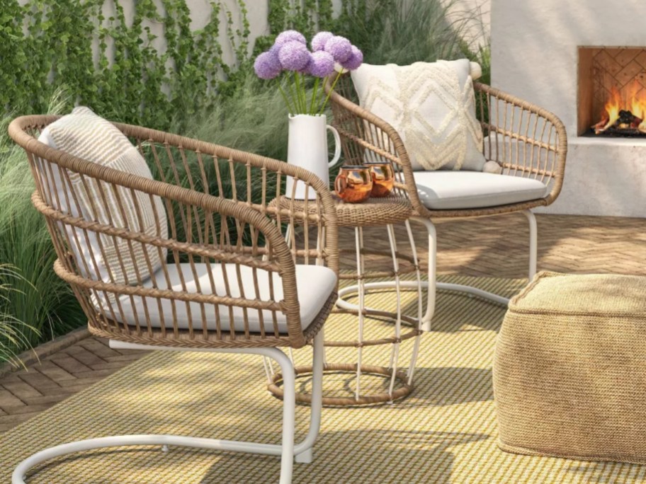 tan and white rattan patio chairs and side table on back deck