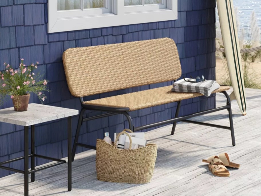 wicker and metal outdoor bench against a navy blue house by the beach 