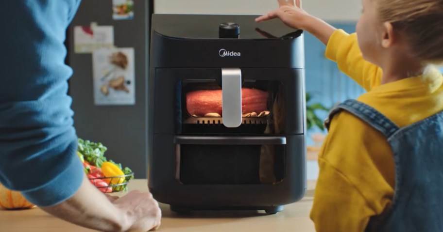dad and little girl watching a Midea black dual air fryer cook food