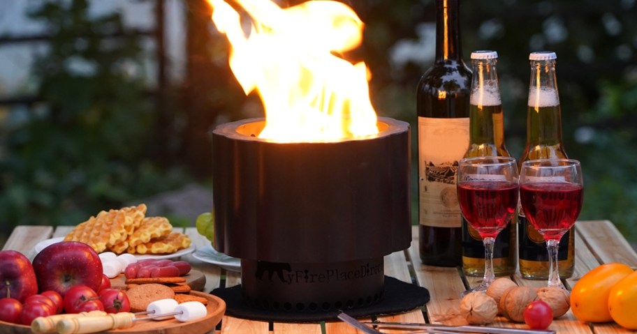 small black tabletop mini fire pit lit up on a table with food and drinks